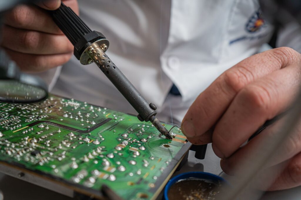 Component-Level Repair for Heavy Machinery Technician performing precise soldering on a circuit board for electronics repair.